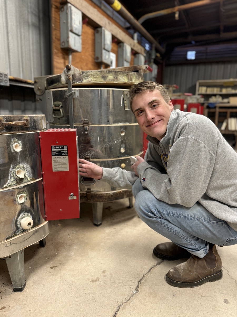Joey Downey beside ceramic kilns in the studio